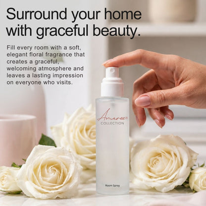 A hand sprays a frosted room spray bottle from the Amaree Collection, surrounded by white roses and set against a soft, blurred background with promotional text.